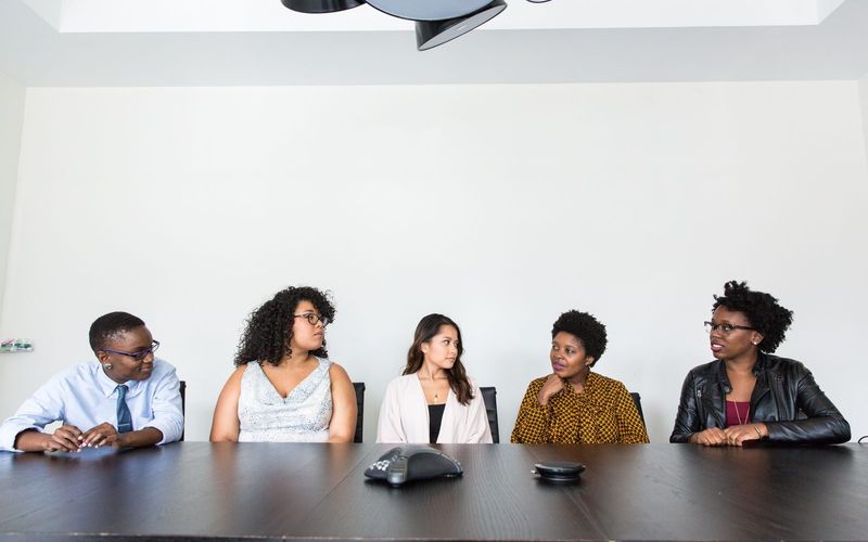 Five people seated at a conference table during a discussion