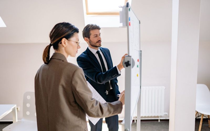 Two colleagues planning a course on a whiteboard