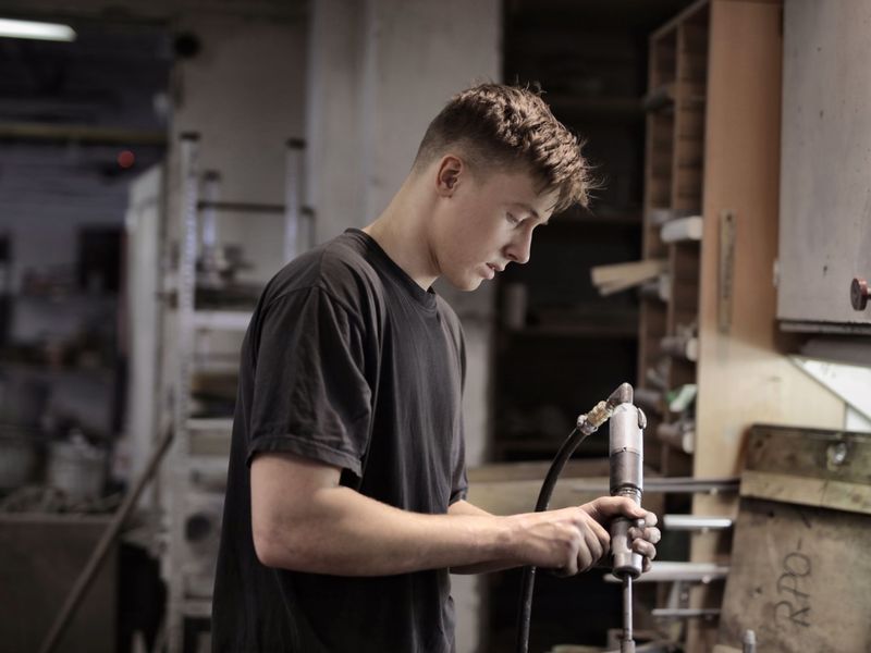 A young trainee practising a hands-on technical task in a workshop
