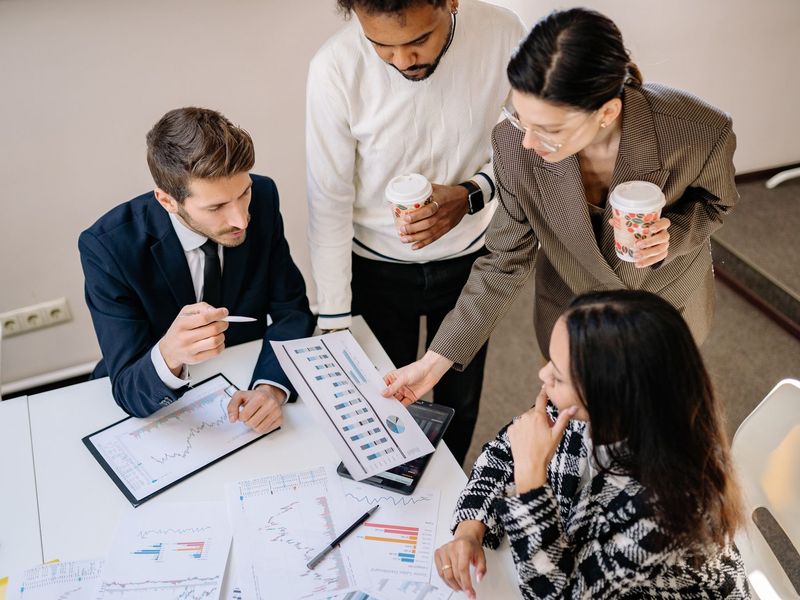 Four colleagues reviewing printed reports together at a table