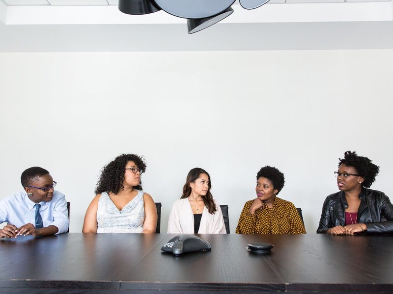Five colleagues talking around a meeting table with a conference phone
