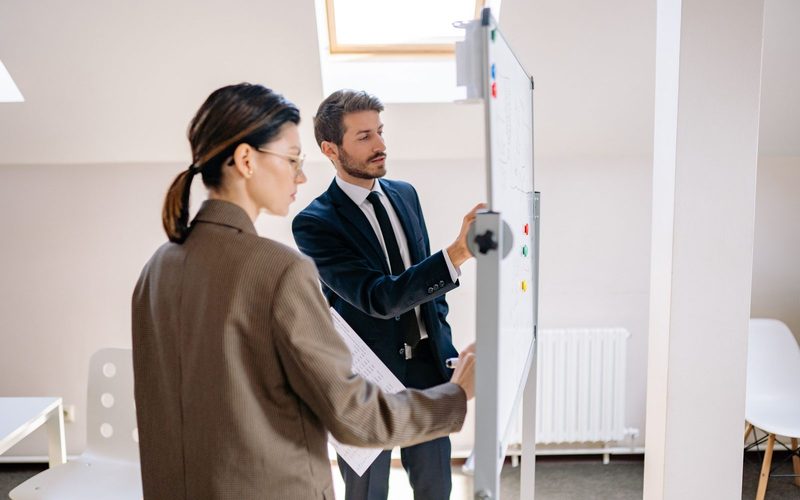 Two colleagues mapping out a course plan on a whiteboard